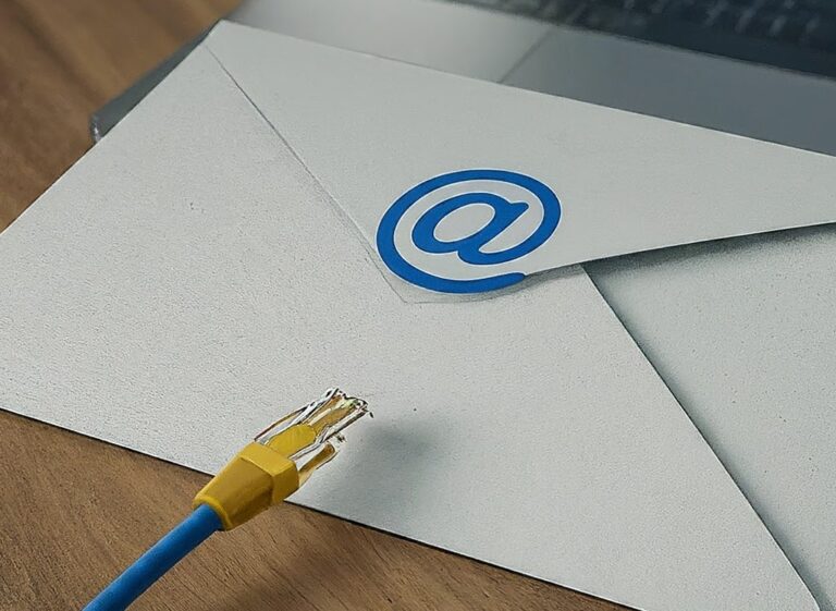 Envelope with @ symbol stamped on it, a network cable end resting on envelope